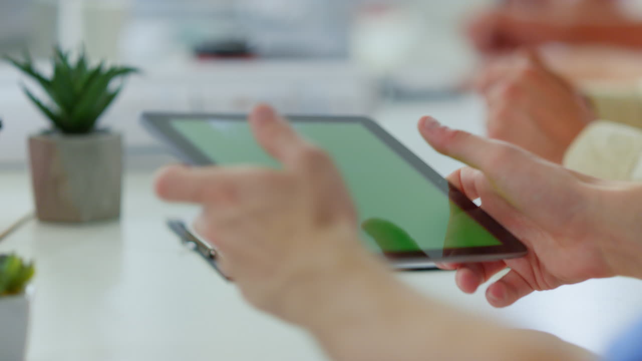 실내에서 녹색 화면 태블릿을 사용하는 남자의 손. 알려지지 않은 사람이 터치 스크린.