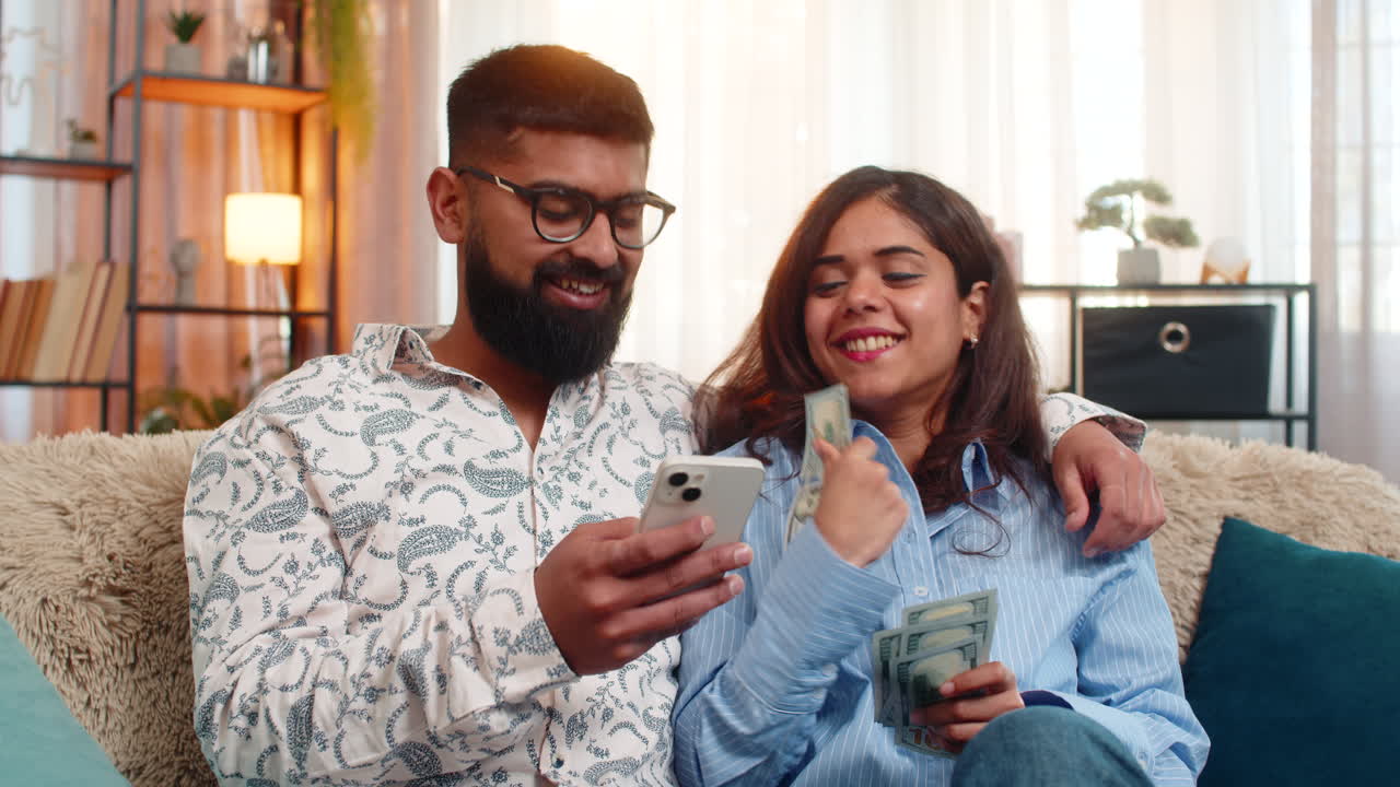 Indian family couple man woman planning expenses with cash and smartphone discussing shopping salary