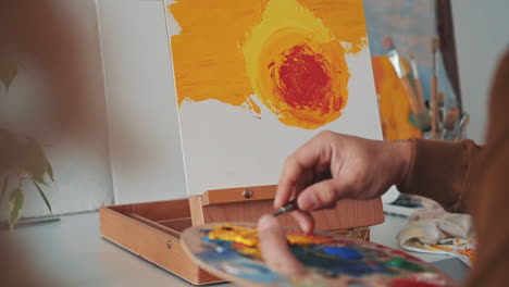 an unrecognizable man painting with a spatula on a canvas 1