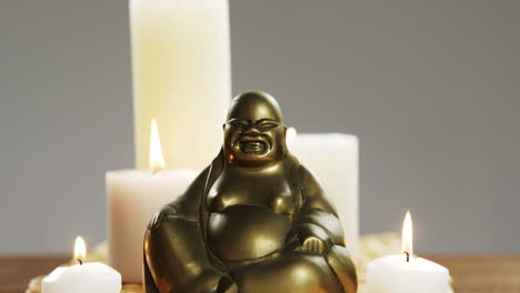 close-up of laughing buddha figurine with burning candles