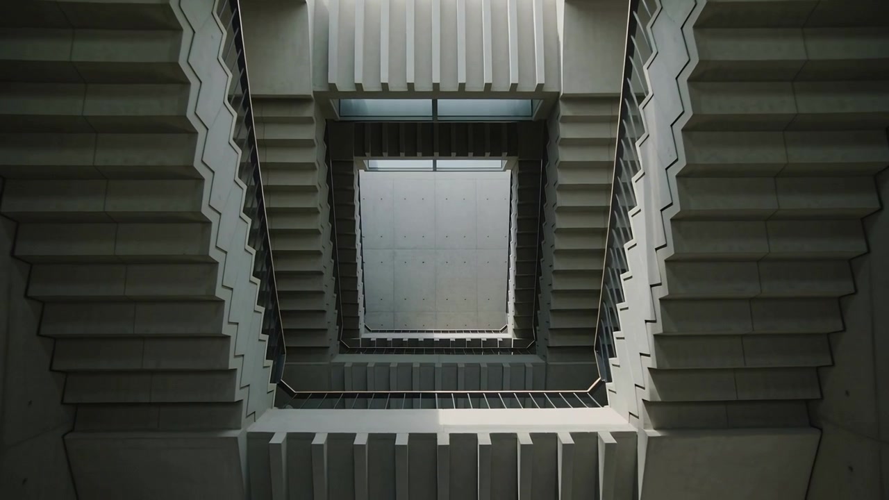 Caméra inclinée montant à travers les volées d'escaliers à l'intérieur d'un atrium, cadrant une lucarne carrée et des garde-corps