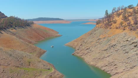 Erstaunliche-Luftaufnahme-über-Dem-Von-Dürre-Betroffenen-Kalifornischen-See-Oroville-Mit-Niedrigem-Wasserstand,-Zurückweichender-Küstenlinie-Und-Verbrannten-Bäumen-Und-Wäldern