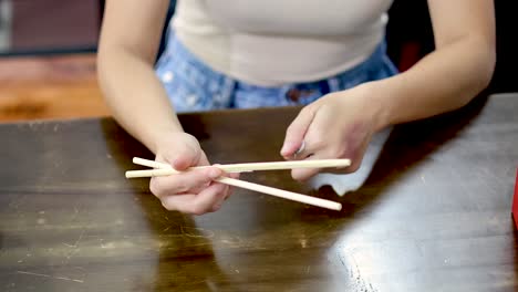 person unwrapping and preparing chopsticks for use