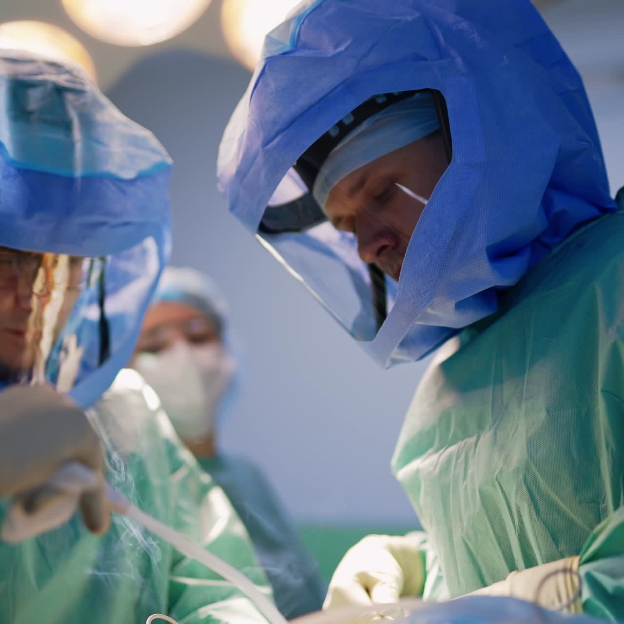 Un team chirurgico indossa caschi protettivi durante un'operazione ortopedica. I medici utilizzano un dispositivo medico e si alza del fumo bianco