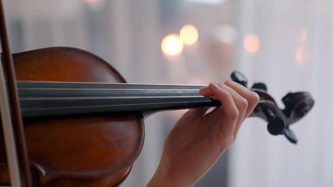 Primo piano della mano di un musicista che suona le corde del violino