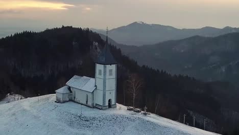 Vista-De-La-Iglesia-Jamnik-En-Un-Paisaje-Invernal-Con-Un-Colorido-Amanecer-En-Kranj,-Eslovenia