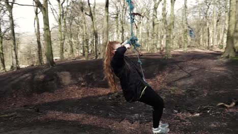 pretty young woman swinging on rope swing in british woodland-1