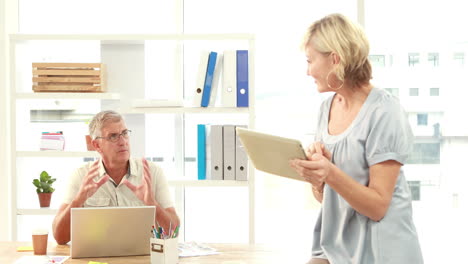 Smiling-casual-colleagues-using-digital-tablet-in-office