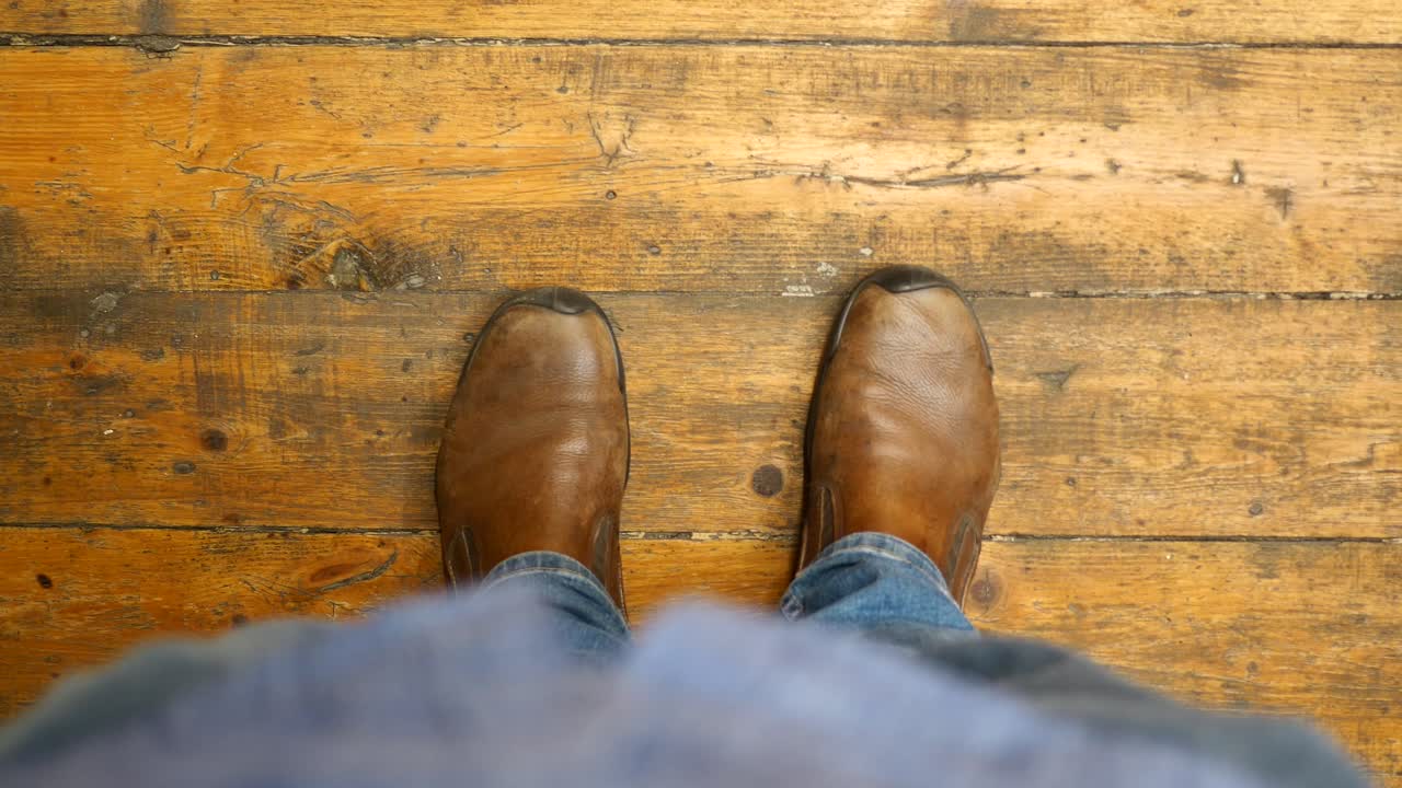 갈색 부츠와 청바지를 입고 나무 바닥에 서 있는 사람