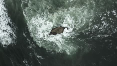 strong ocean currents hitting rock in pacific city beach, oregon, usa