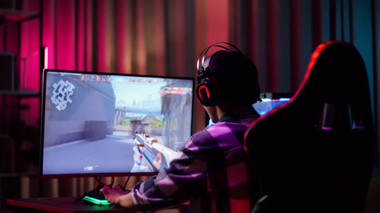 Asian Teen Boy Gamer Wearing Head Phones And Playing Video Game On Computer, Shooter Online Video Game