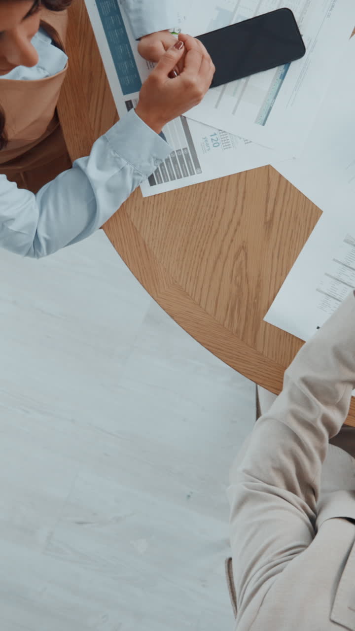 Overhead View of Business Professionals Discussing Documents at a Meeting