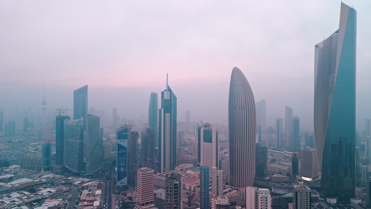 Vista aerea con drone dello skyline del centro di Kuwait City nella foschia mattutina, torri moderne iconiche e quartiere degli affari sotto un cielo rosa tenue all'alba per immagini di viaggi, finanza e contesto urbano