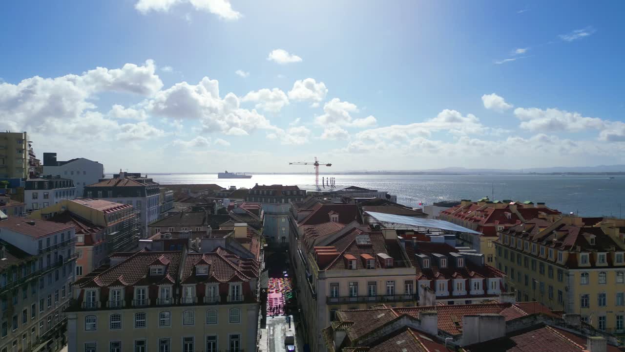Volo all'indietro sopra la strada rosa situata a Cais do Sodre nella città di Lisbona con gabbiani in volo e il fiume Tago come sfondo e lo skyline di Lisbona, Portogallo.