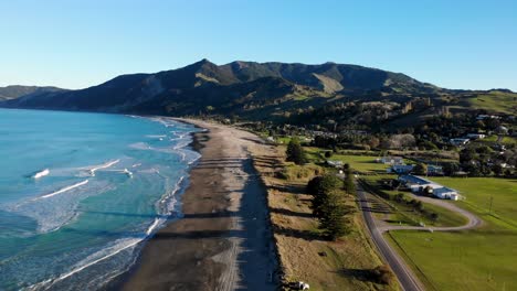 Birds-eye-view-of-amazing-sandy-beach,-calm-blue-ocean,-hills-on-horizon