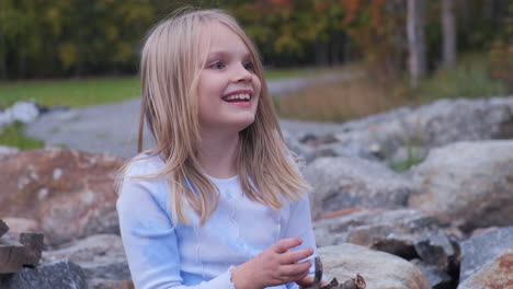 close up static shot of blonde girl laughing and playing outdoors