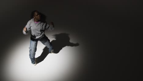 Looking-Down-On-Studio-Shot-Of-Young-Woman-Dancing-In-Spotlight-In-Real-Time