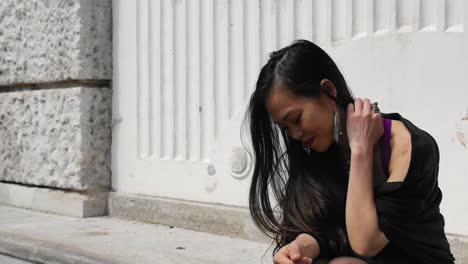 joven asiática en un banco de piedra se rasca el cuello y sonríe