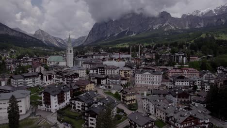 Aerial-Cortina-D'Ampezzo-alpine-village-and-church-Dolomites,-Italy