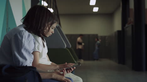 Two-serious-schoolgirls-scrolling-tablet-in-hall.-Technology-in-education.