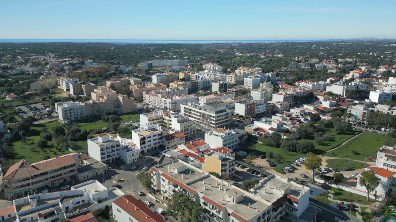 Aerial establishing shot of settlement in Quarteira, Atlantic Ocean in the distance. Algarve