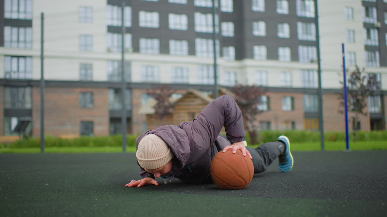 caucasian man outdoor court workout basketball senior street athlete executes onearm pushup and dribble drills on wet asphalt, wearing beanie, jacket and sneakers gritty overcast residential skyline