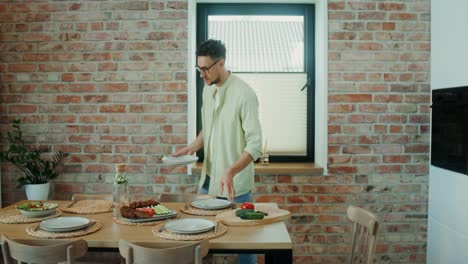 man setting a table with dinner