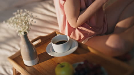 closeup hotel bed breakfast on tray. unknown woman body rest in golden sunlight