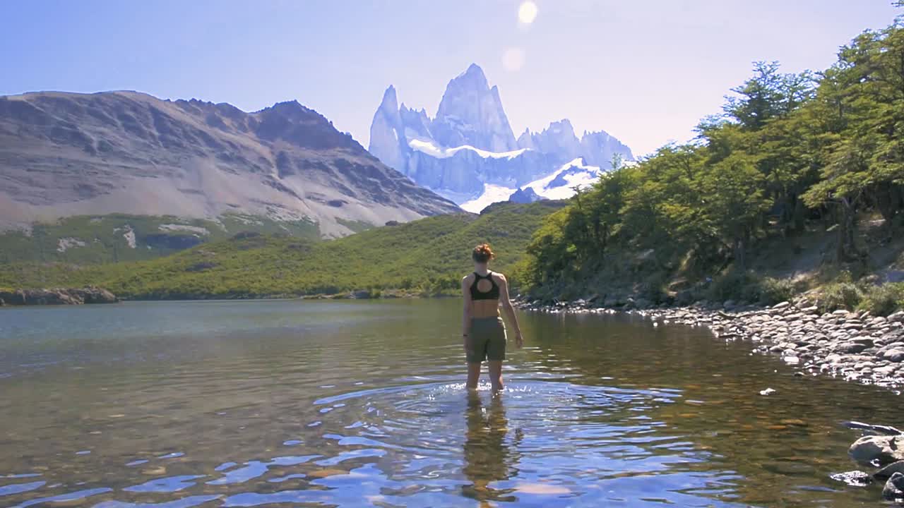 Giovane donna che cammina nel lago nella Laguna Carpi, guardando il Fitz Roy in Patagonia, Argentina