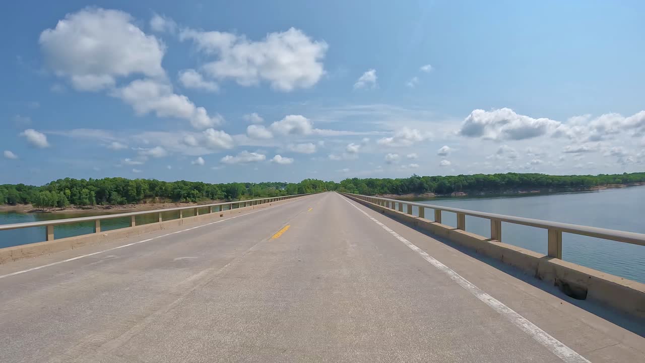 POV - Driving on the bridge over Saylorville Lake near Polk City Iowa on a bright sunny day with light traffic; concepts of flood control, travel and recreation