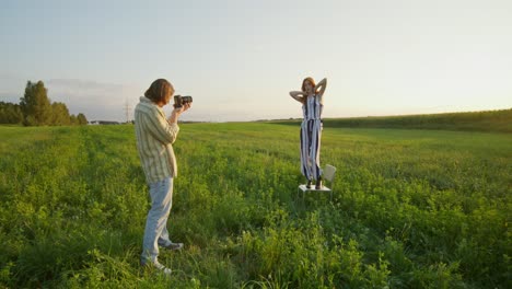 photographer taking photo of model in a field at sunset