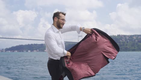 hombre con su chaqueta contra la ciudad junto al mar.