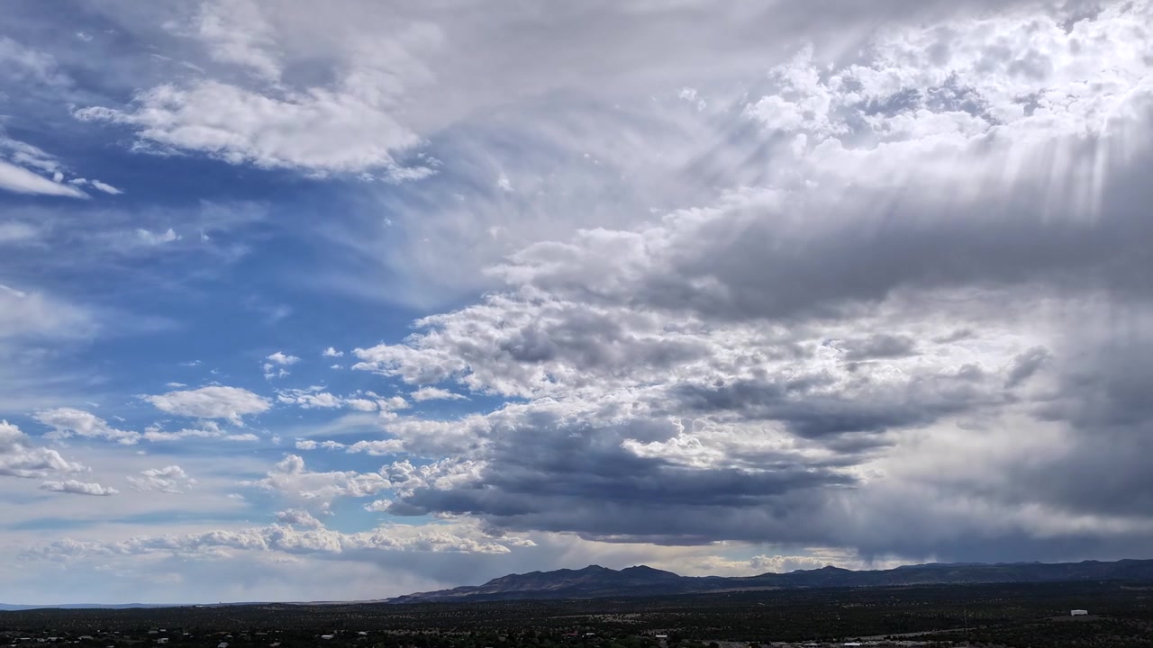 Un mozzafiato timelapse con drone che cattura nuvole spettacolari che si spostano rapidamente nel cielo. Raggi di sole scintillanti irrompono attraverso l'atmosfera, evidenziando un tempo sorprendente.