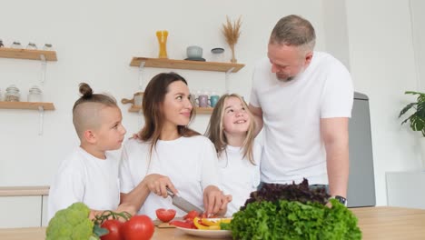 young happy kid talking with mom cooking lunch together cutting vegetables at table family at home young happy kid talking with mom cooking lunch together cutting vegetables at table family at home healthy food organic and nutrition