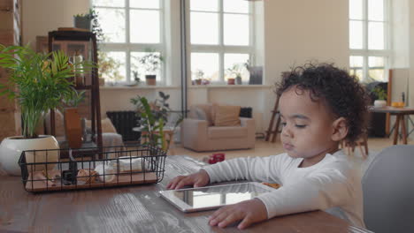 adorable toddler boy sitting at desk with tablet