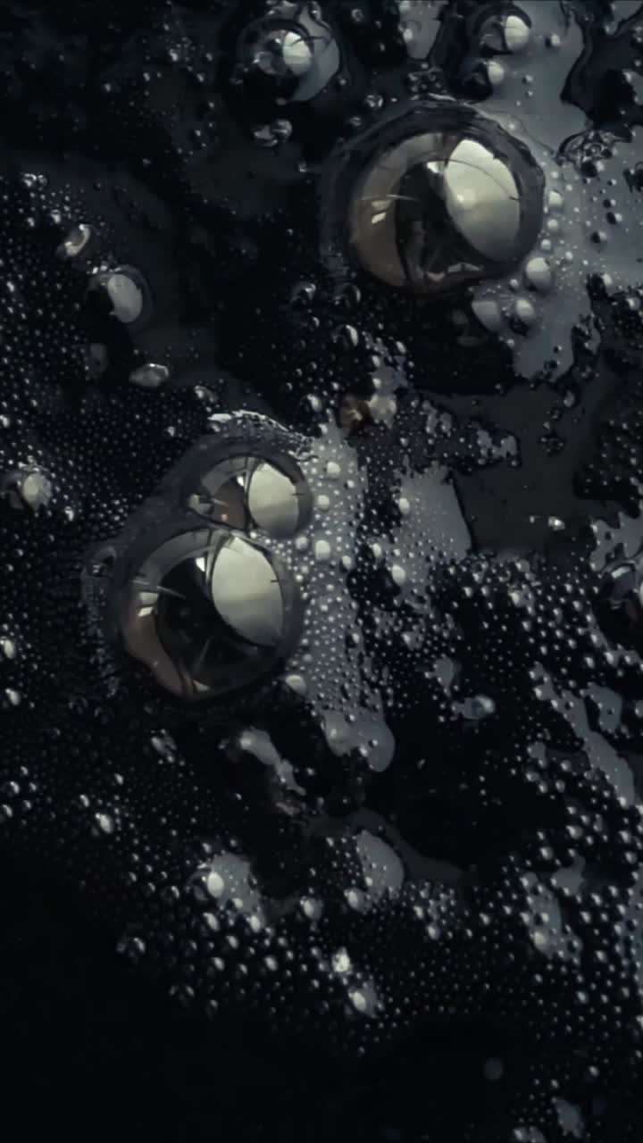 Close-up of Dark Bubbling Liquid Surface with Reflections