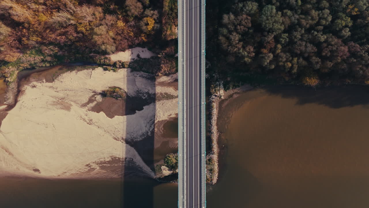 Aerial View of a Bridge Spanning a River through Autumn Forest