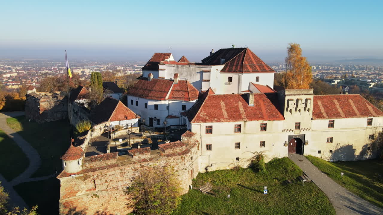 Aerial drone view of The Citadel in Brasov at sunrise, Romania. Medieval fortress on the top of a hill. Buildings, yellowed trees
