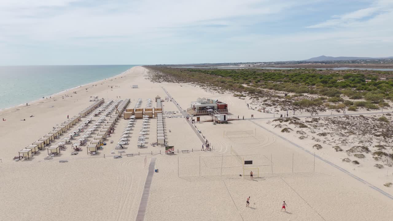 Aerial view of Tavira Island’s beach area featuring a seaside bar and relaxation zone on the golden sands of Portugal’s Algarve