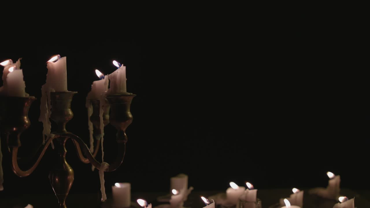 Un gruppo di candele bianche, alcune su un candelabro, accese e poi spente dal vento al rallentatore