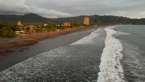 jaco beach, costa rica with waves at sunset- aerial rotation view of beach and coastline