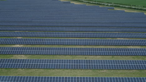 Establishing-Drone-Shot-Over-Field-of-Solar-Panels-on-Solar-Farm-with-Road-Behind