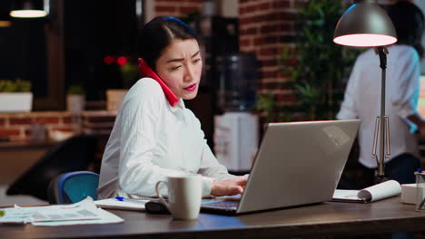 Secretaria-De-La-Empresa-Atendiendo-Llamadas-Telefónicas-En-El-Escritorio-De-La-Oficina,-Respondiendo-Consultas-De-Los-Clientes