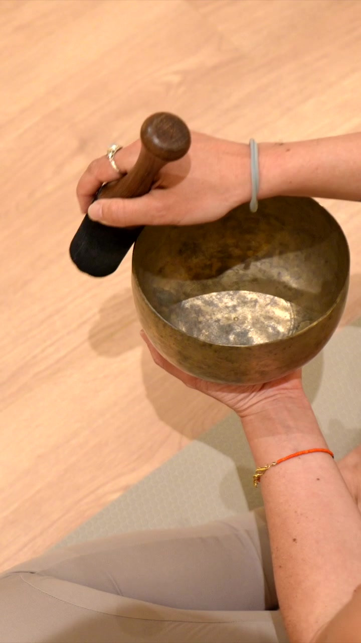 Primo piano di mani che suonano una campana tibetana per la meditazione