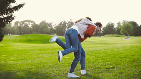 happy couple spinning around and then hugging in the park