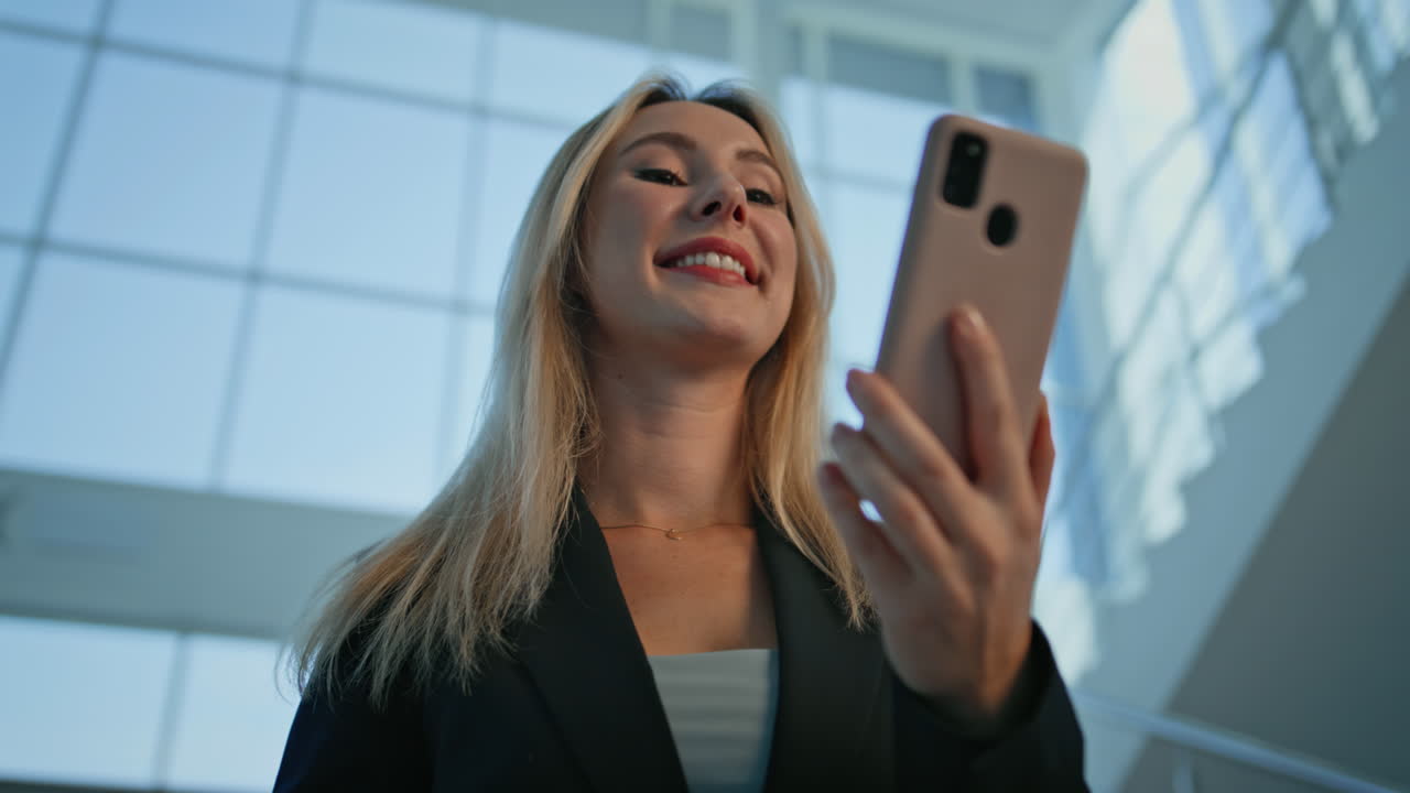 Primo piano di una manager che legge un messaggio sullo smartphone nell'illuminata hall di un ufficio