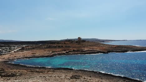 vista aérea hacia la playa de coral, torre blanca en mellieha armier bay, malta