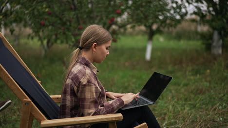busy freelancing female employee typing on her laptop. lady finishes work leaning backwards in the chair. man using smartphone at backdrop.