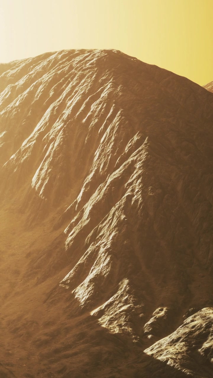 Catena montuosa con una texture marcata sotto la luce solare gialla al tramonto.