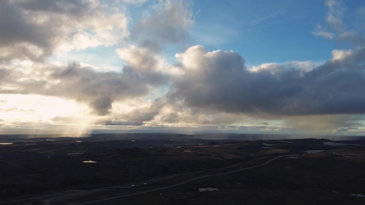Aerial drone shot capturing golden sunbeams penetrating cloud layer over vast barren tundra landscape